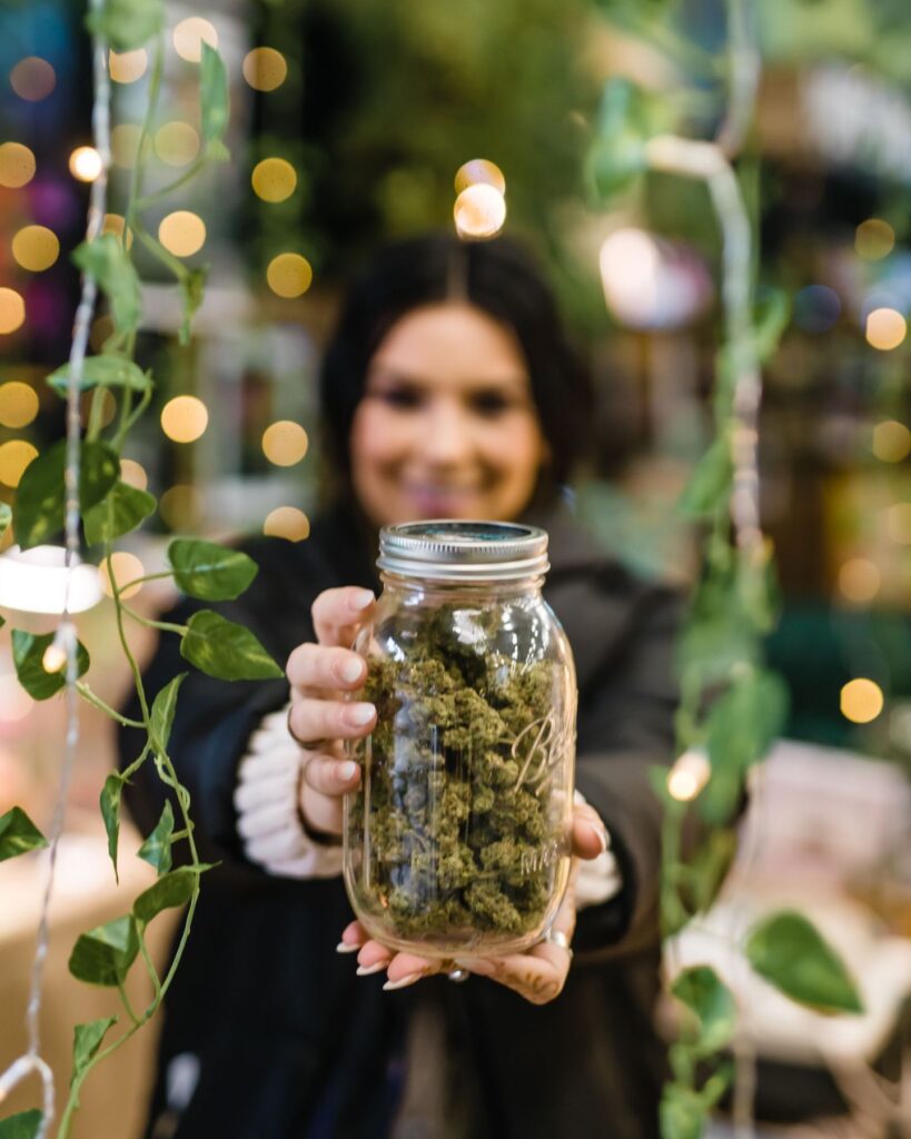 A woman offers a jar of cannabis to the camera at The Emerald Cup 2021. (Photo by Demian Becerra, Courtesy The Emerald Cup)