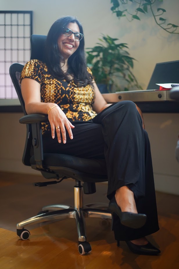 Shaleen Title sitting in an office chair in an executive setting and smiling