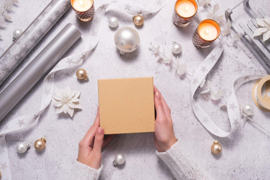 A woman holds a gift box among silvery and white jewelry. Preparing for Christmas and New Years.