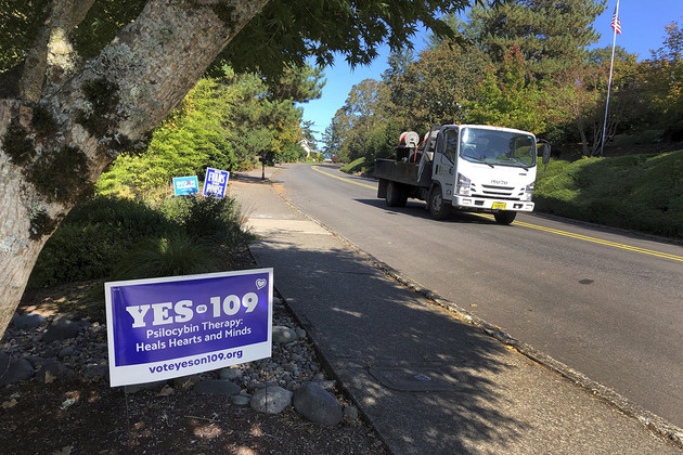 A truck drives past a sign supporting a ballot measure that would legalize controlled, therapeutic use of psilocybin mushrooms.